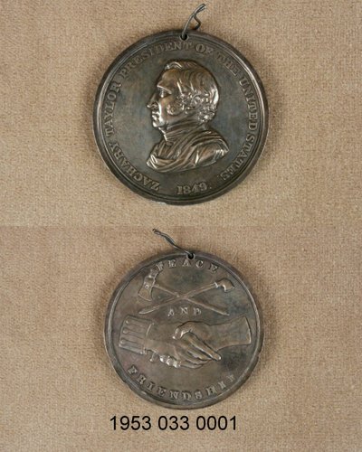 Silberne Friedensmedaille/Vorderseite mit Büste von Zachary Taylor/Rückseite mit gekreuzter Pfeife und Beil über verschränkten Händen, eine mit Uniformmanschette von Unknown